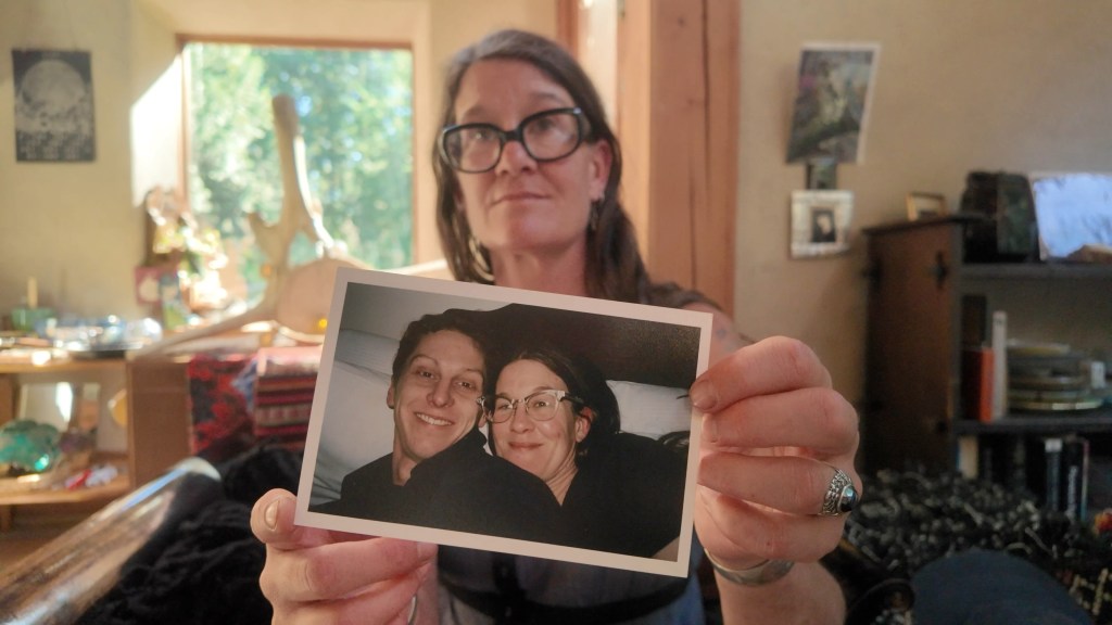 Woman holding up a photo of herself and her late partner